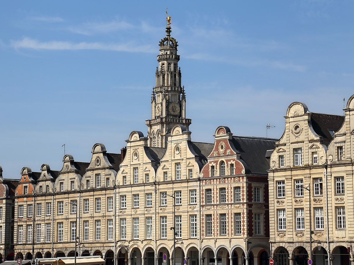 Blick auf den historischen Marktplatz von Arras, Frankreich, mit dem imposanten Belfried und den Giebelhäusern unter blauem Himmel.