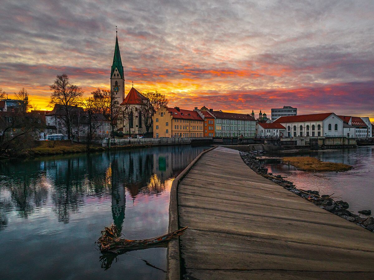 Malerischer Sonnenuntergang in Landshut, Deutschland, mit der Stiftskirche St. Martin, Isar und Uferweg.