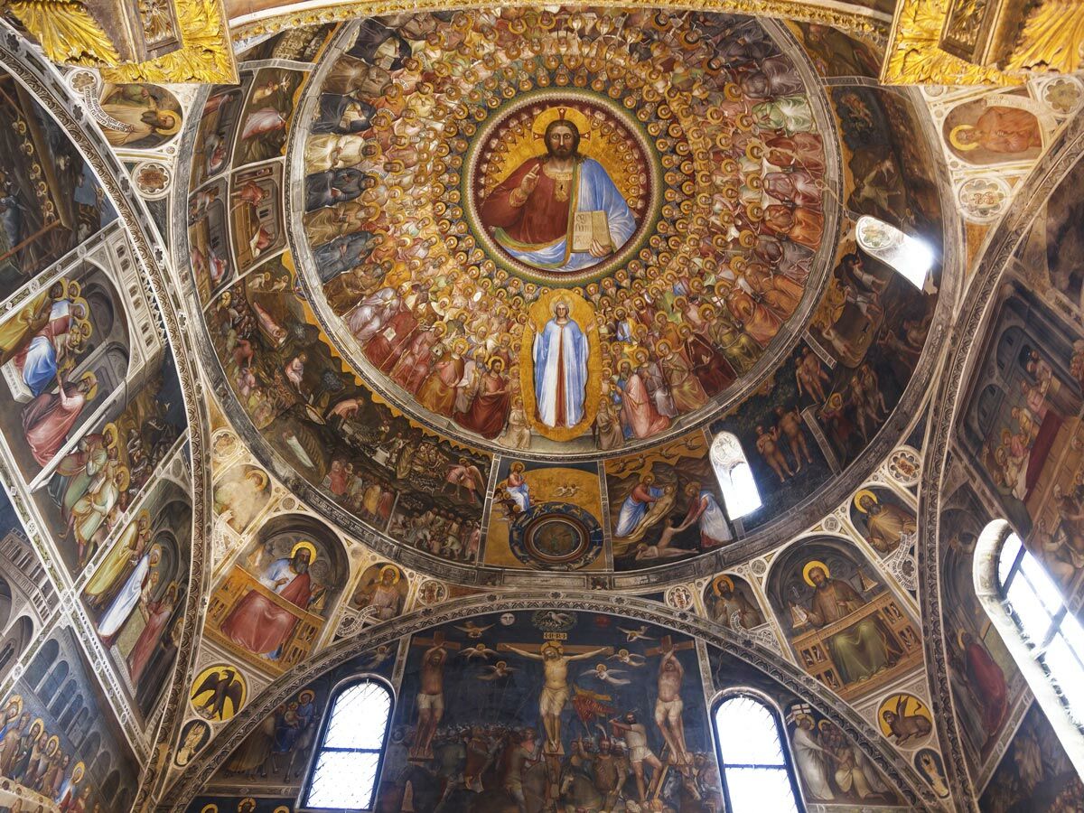 Blick auf eine prächtige, bemalte Kirchenkuppel mit Fresken, die Christus, Heilige und biblische Szenen im Stil der Renaissance zeigen.