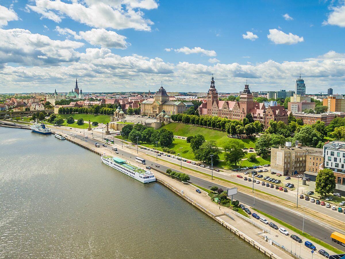 Luftaufnahme von Szczecin mit Wały Chrobrego, Oder und historischen Gebäuden an einem sonnigen Tag. Schiffe am Kai, geschäftige Straße.