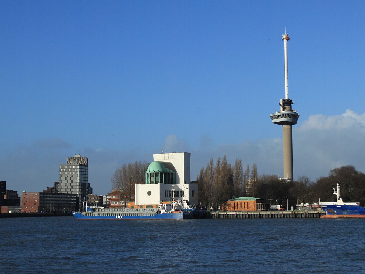 Blick auf Rotterdams Skyline mit Euromast, Nieuwe Maas, Schiffen und Gebäuden bei blauem Himmel.
