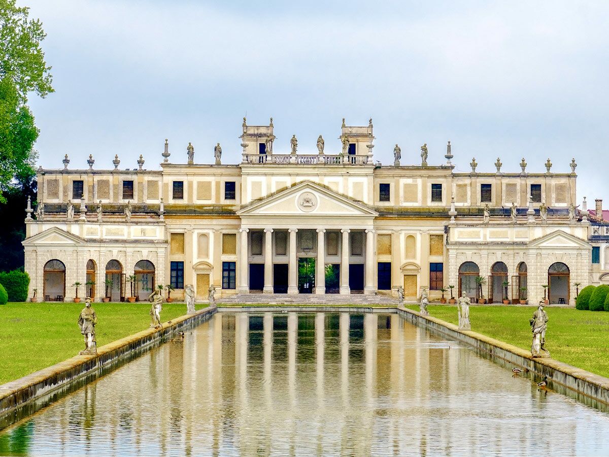 Majestätische Villa Pisani in Stra mit Reflexionsbecken, Statuen und weitläufigem Garten unter hellem Himmel.