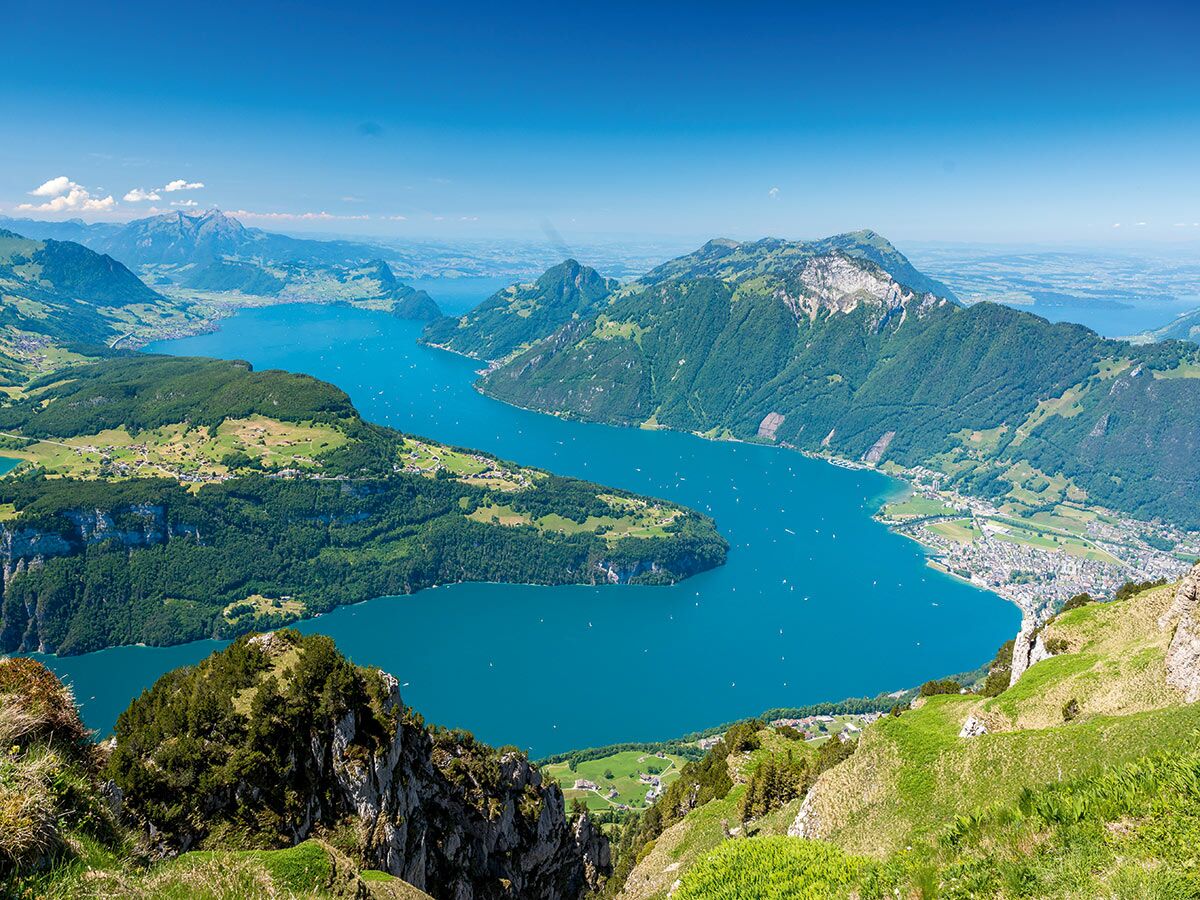 Panoramablick Vierwaldstättersee, Schweiz, mit blauem Wasser, grünen Alpenhängen, Dörfern und Booten.