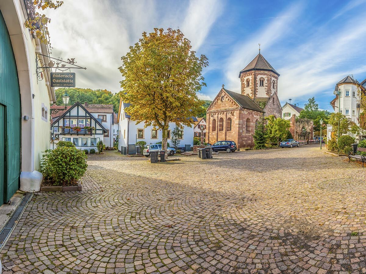 Malerischer Dorfplatz mit historischer Kirche, Fachwerkhäusern und Kopfsteinpflaster im Herbst in einem deutschen Dorf.