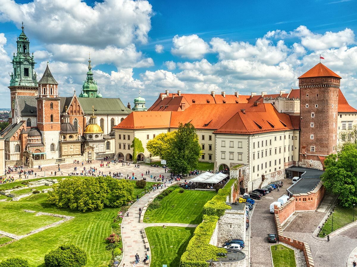 Wawel-Kathedrale und Königsschloss in Krakau, Polen. Historische Gebäude, grüne Gärten, viele Touristen unter blauem Himmel.