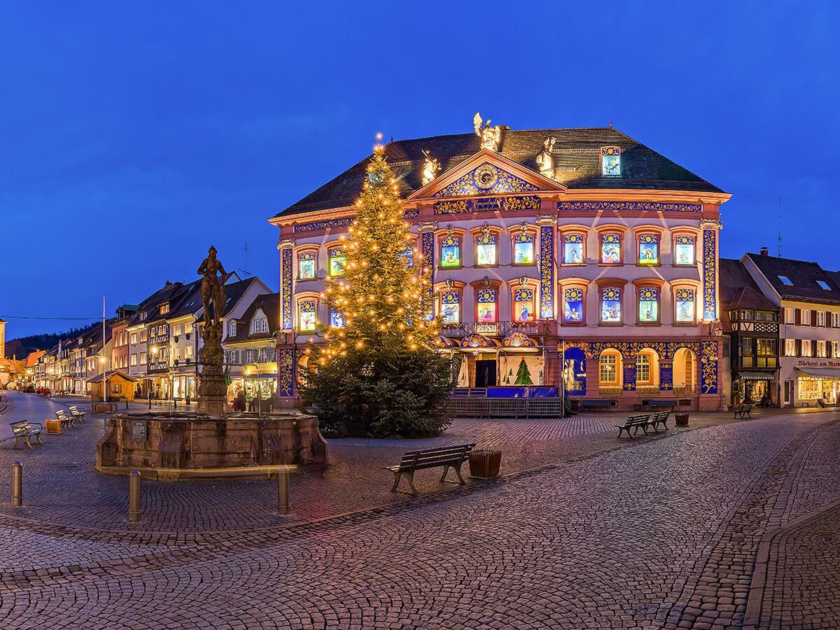 Beleuchteter Weihnachtsbaum vor historischem Rathaus Gengenbach am Marktplatz mit Brunnen bei winterlicher Abendstimmung.