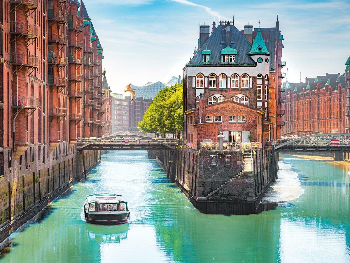 Hamburg Speicherstadt: Historische Backsteingebäude säumen einen lebhaften Kanal mit Boot und Möwe unter blauem Himmel.