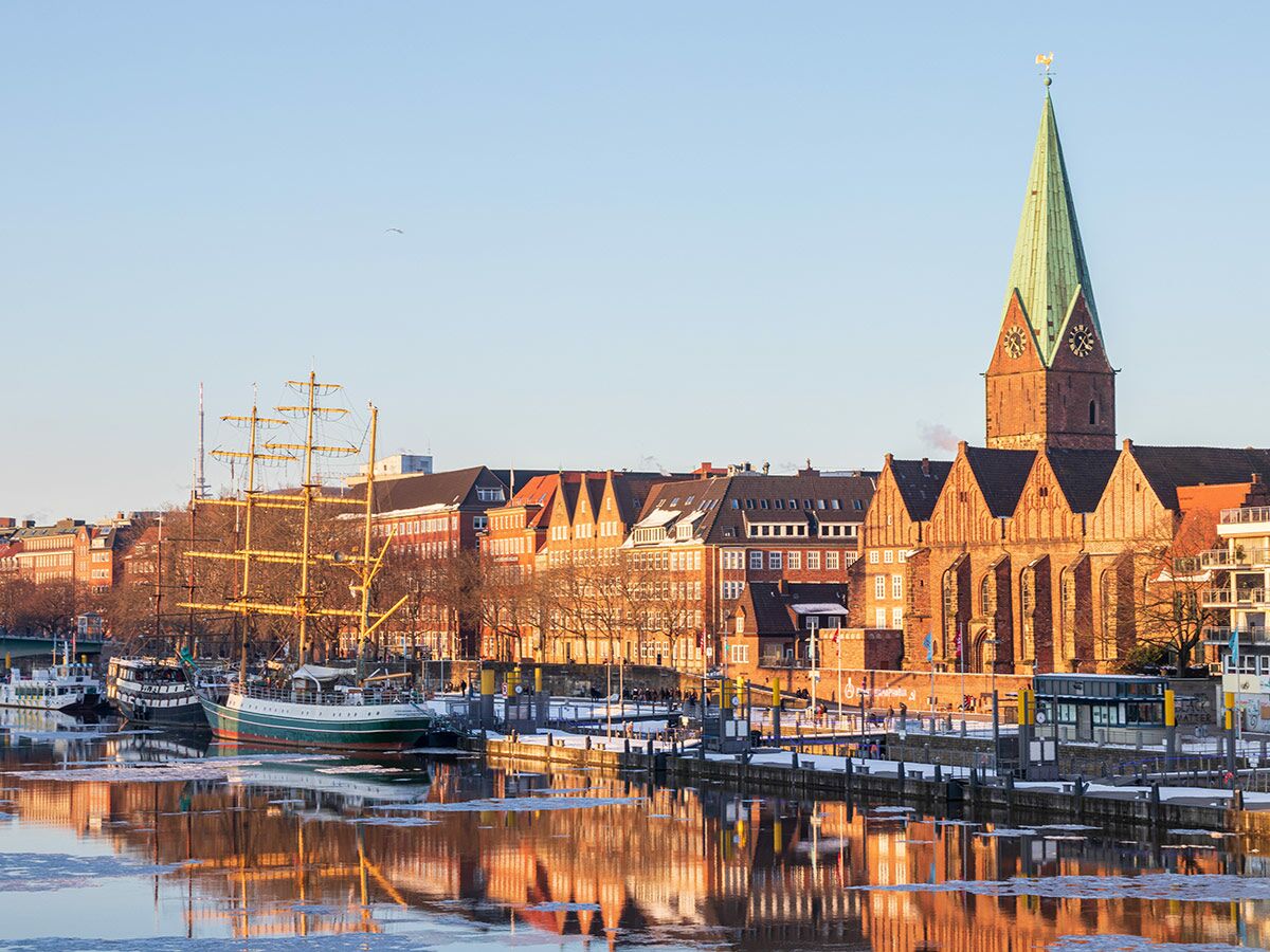 Historische Bremer Altstadt am Fluss Weser mit der St. Martin Kirche, einem Segelschiff und winterlichen Reflexionen.