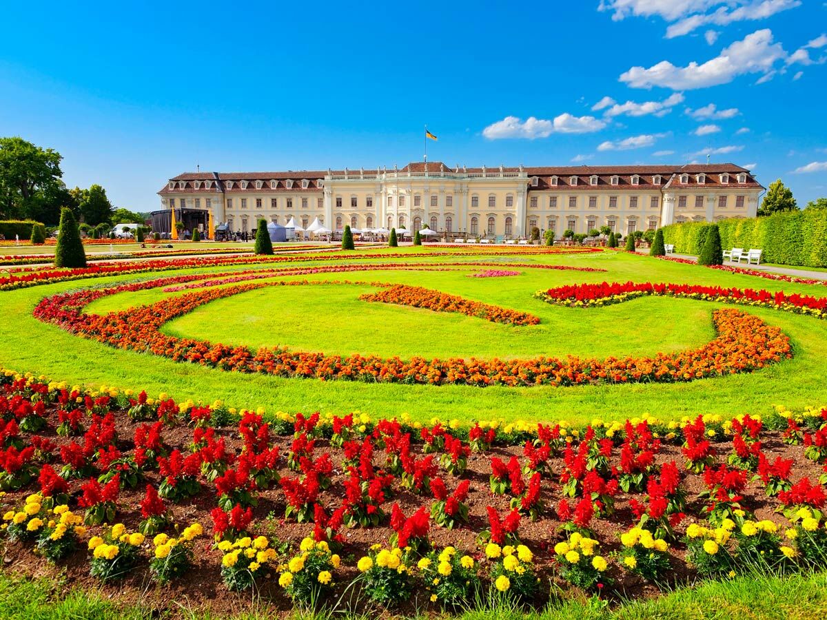 Barockgarten Blühendes Barock Ludwigsburg Schloss mit bunten Blumenbeeten, Rasenflächen und prächtigem Schlossgebäude bei Sonnenschein.