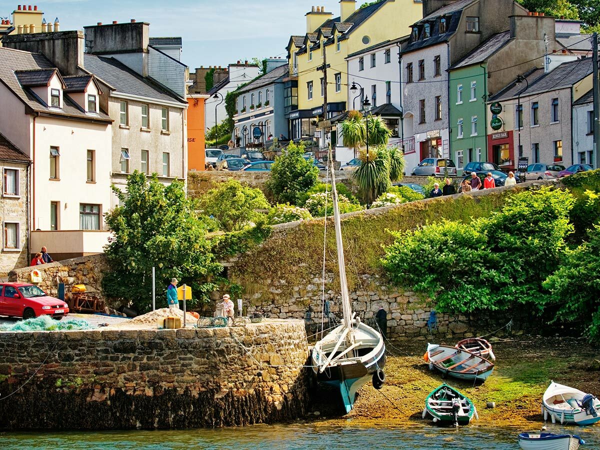 Malerische Küstenstadt mit bunten Häusern, die einen Hafen überblicken. Mehrere Boote liegen bei Ebbe auf dem Grund.