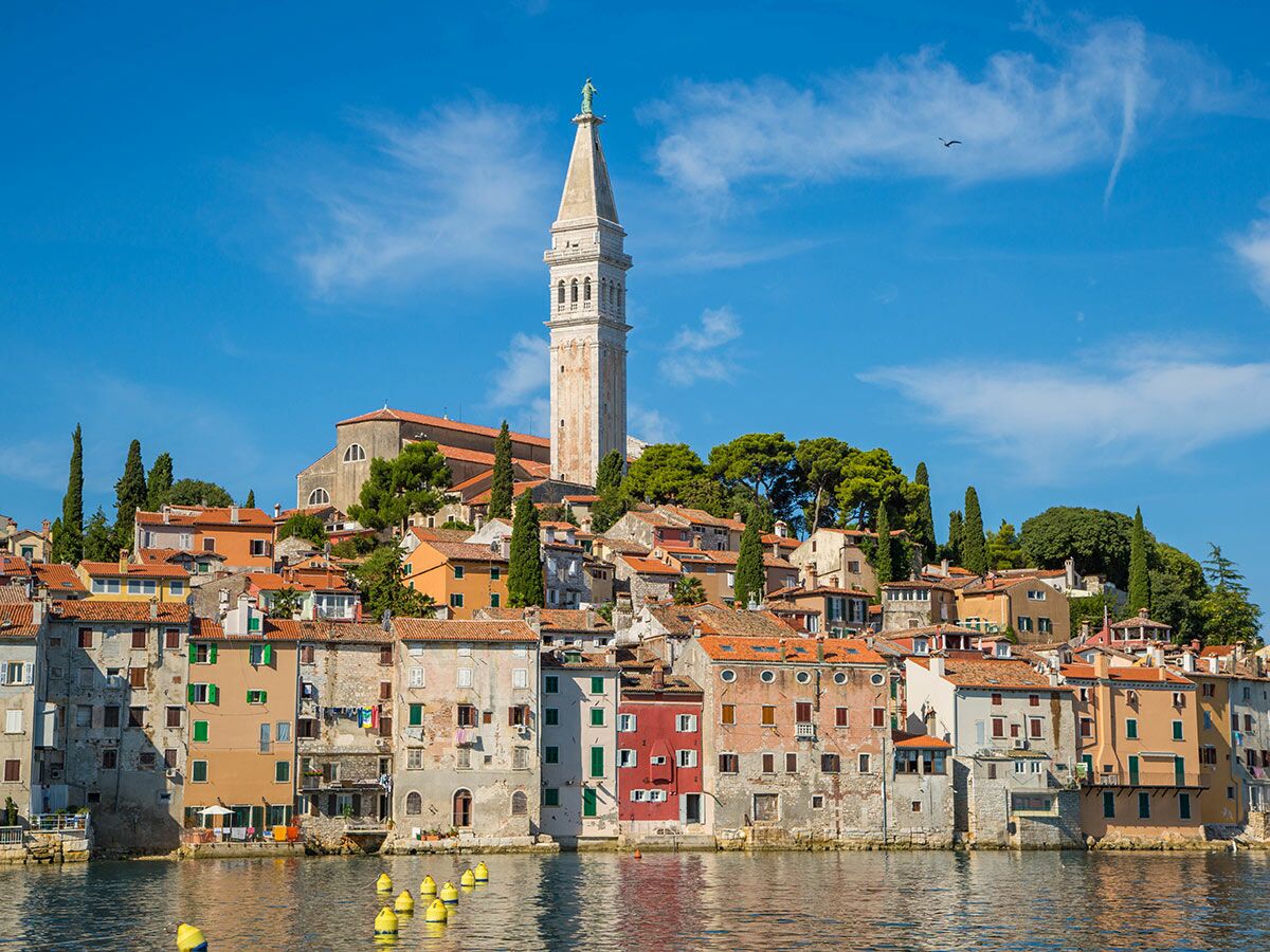 Panoramablick auf Rovinj in Kroatien mit bunt gestrichenen Häusern, historischem Glockenturm und klarem Wasser.