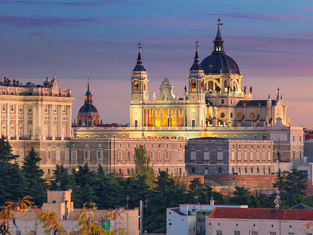 Majestätische Almudena Kathedrale und Königspalast in Madrid bei Sonnenuntergang, beleuchtet mit warmem Licht.