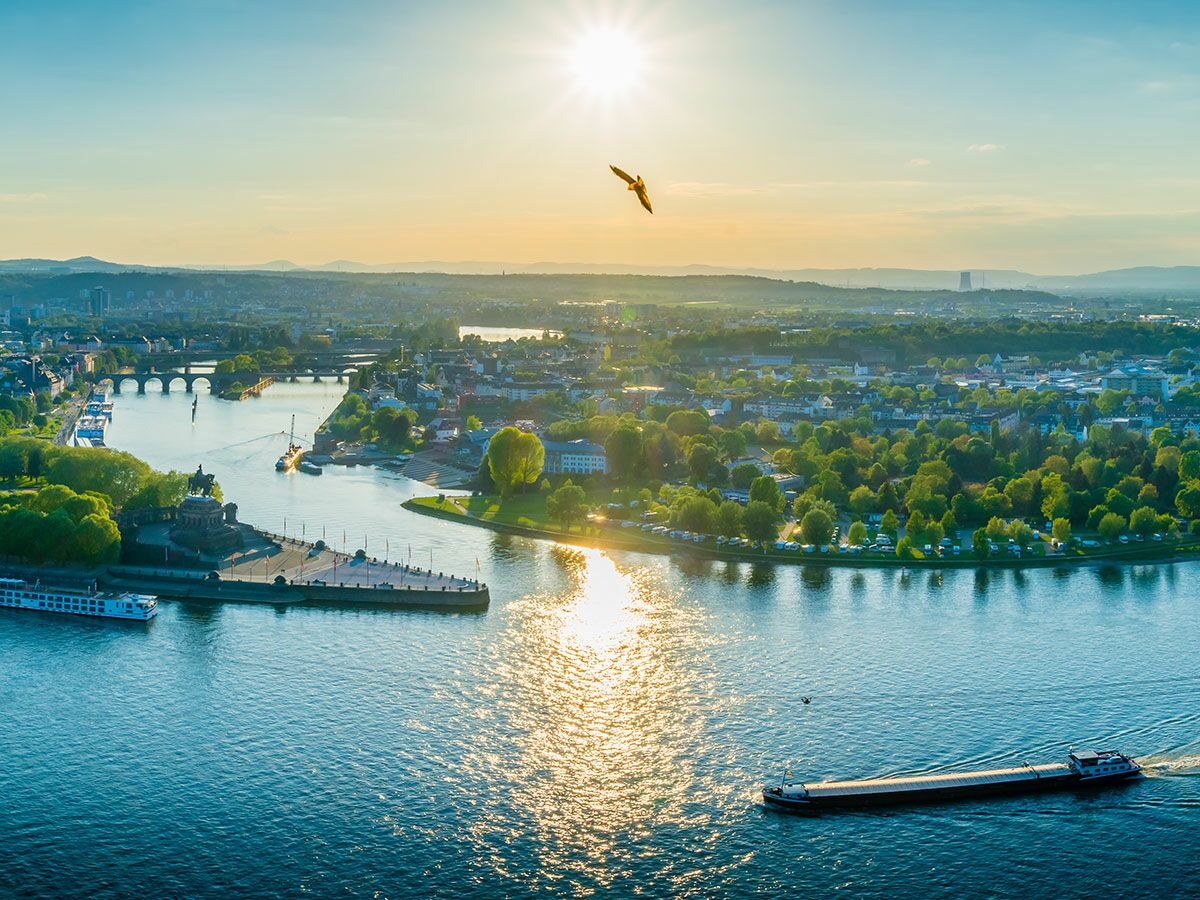 Luftaufnahme von Koblenz am Deutschen Eck mit Rhein und Mosel, Schiffen, Brücken und Denkmal im warmen Abendlicht.