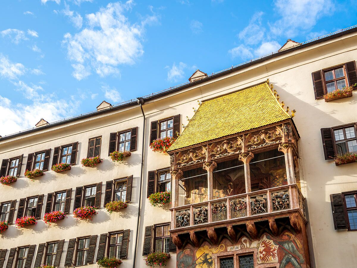 Das Goldene Dachl in Innsbruck, Österreich, mit glänzenden Kupferschindeln, verziertem Balkon und blauem Himmel.