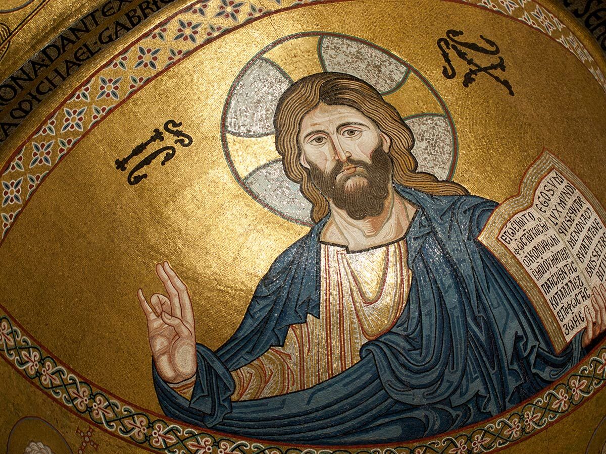 Goldenes Mosaik von Jesus Christus Pantokrator mit Bart, Heiligenschein, segnender Geste und offenem Evangelium in einer Kirche.