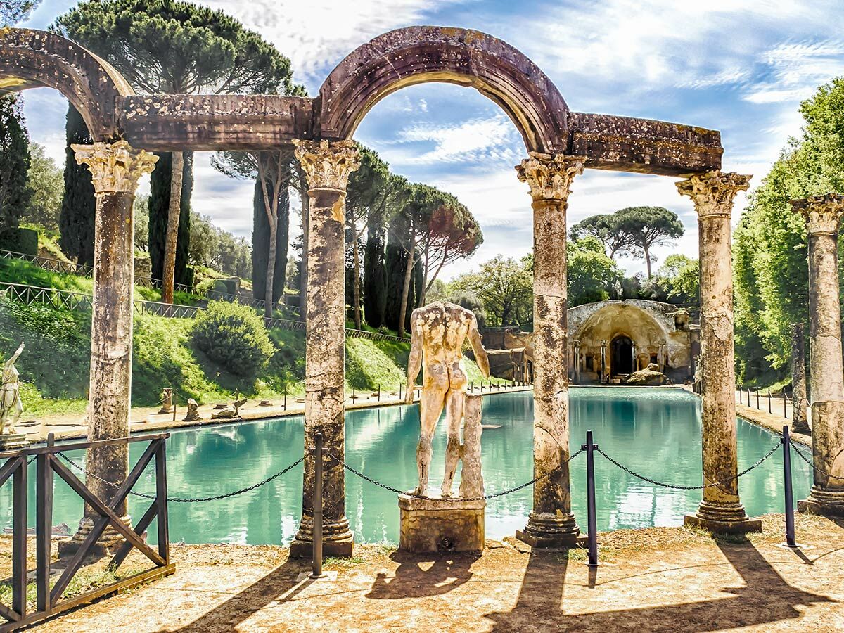 Historischer Garten der Villa d'Este in Tivoli, Italien. Blick durch Bögen auf türkisen Pool, kopflose Statue und Grotte.