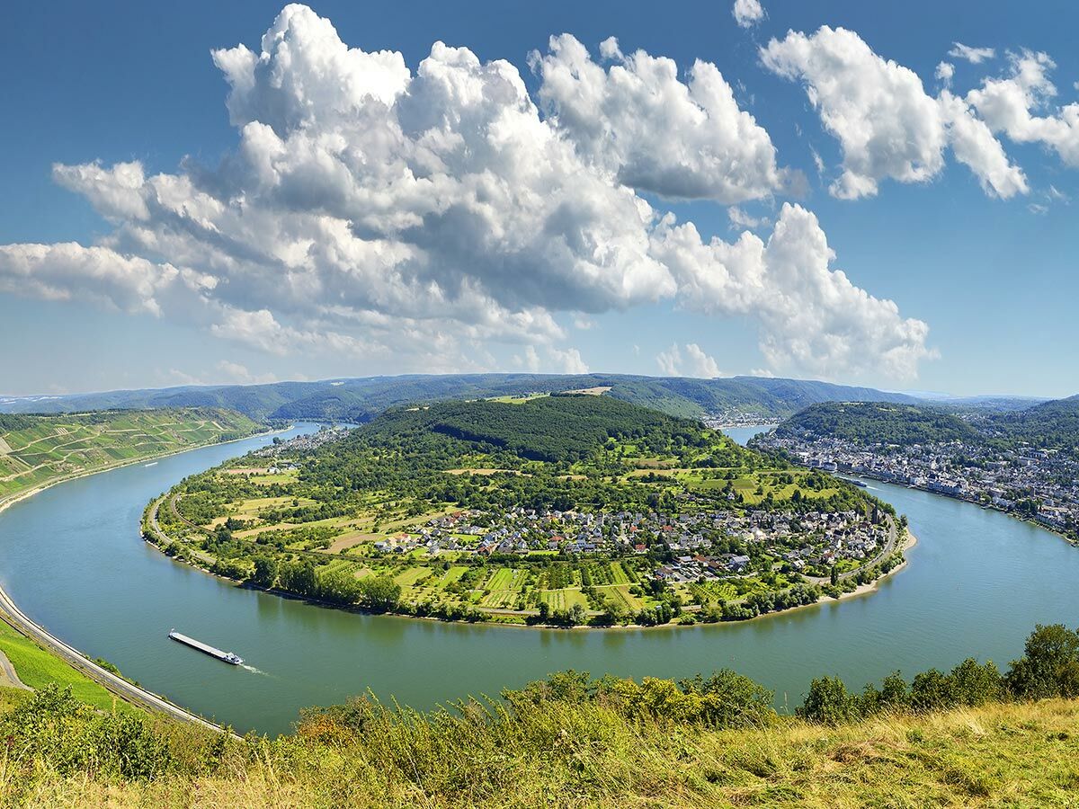 Panoramablick auf die berühmte Rheinschleife bei Boppard mit einem Dorf, Weinbergen und einem Frachtschiff.