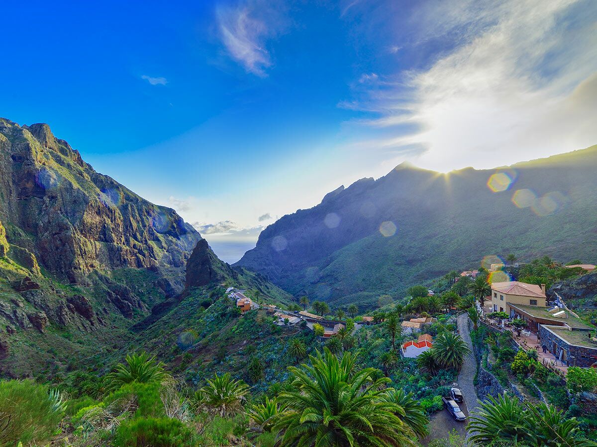 Atemberaubendes Masca Tal auf Teneriffa mit grünen Bergen, Dorf, Palmen und Sonnenuntergang über dem Meer.