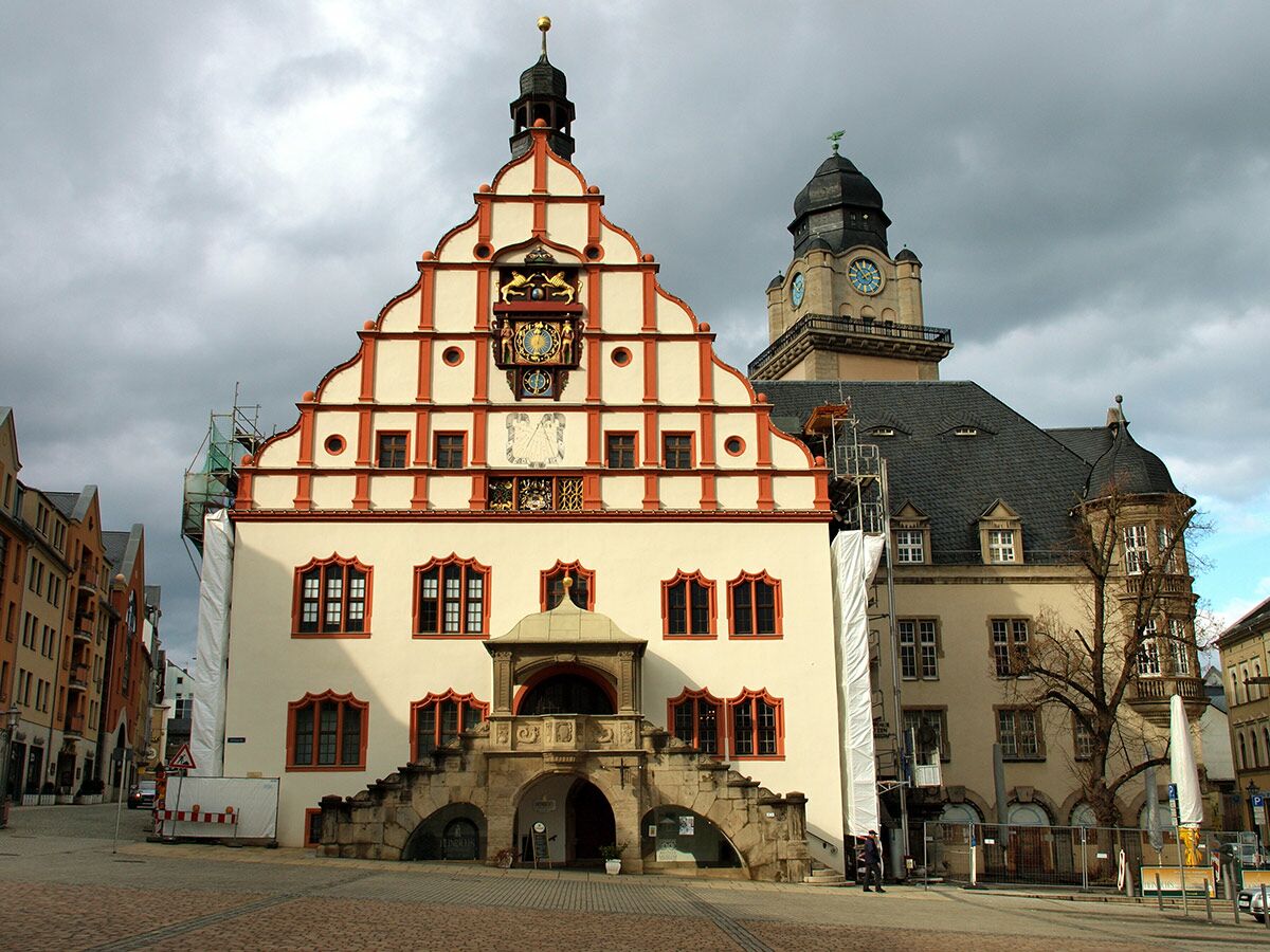 Historisches Rathaus mit markantem Stufengiebel und astronomischer Uhr an einem deutschen Marktplatz unter bewölktem Himmel.