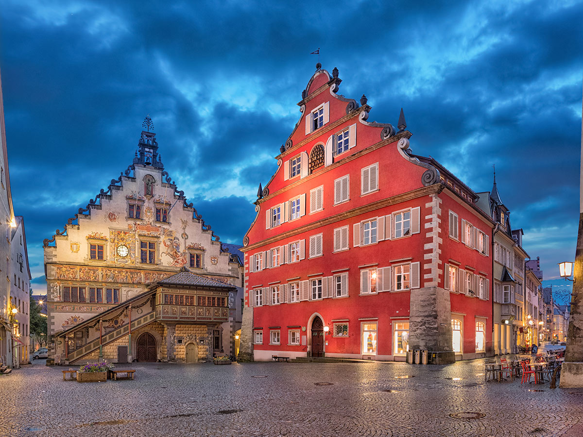Historisches Altes Rathaus und Humpis-Haus in Ravensburg bei Abenddämmerung, beleuchteter Marienplatz mit Kopfsteinpflaster.